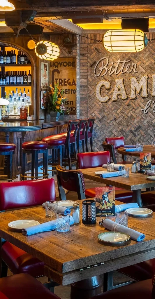 Rustic restaurant interior with red chairs, wooden tables, and a stocked bar.
