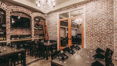 Upscale restaurant interior with brick walls, arched wine displays, crystal chandelier.