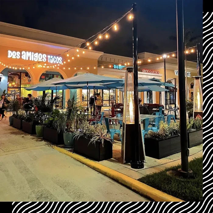 Dos Amigos Tacos outdoor patio at night with umbrellas, lights, heaters.