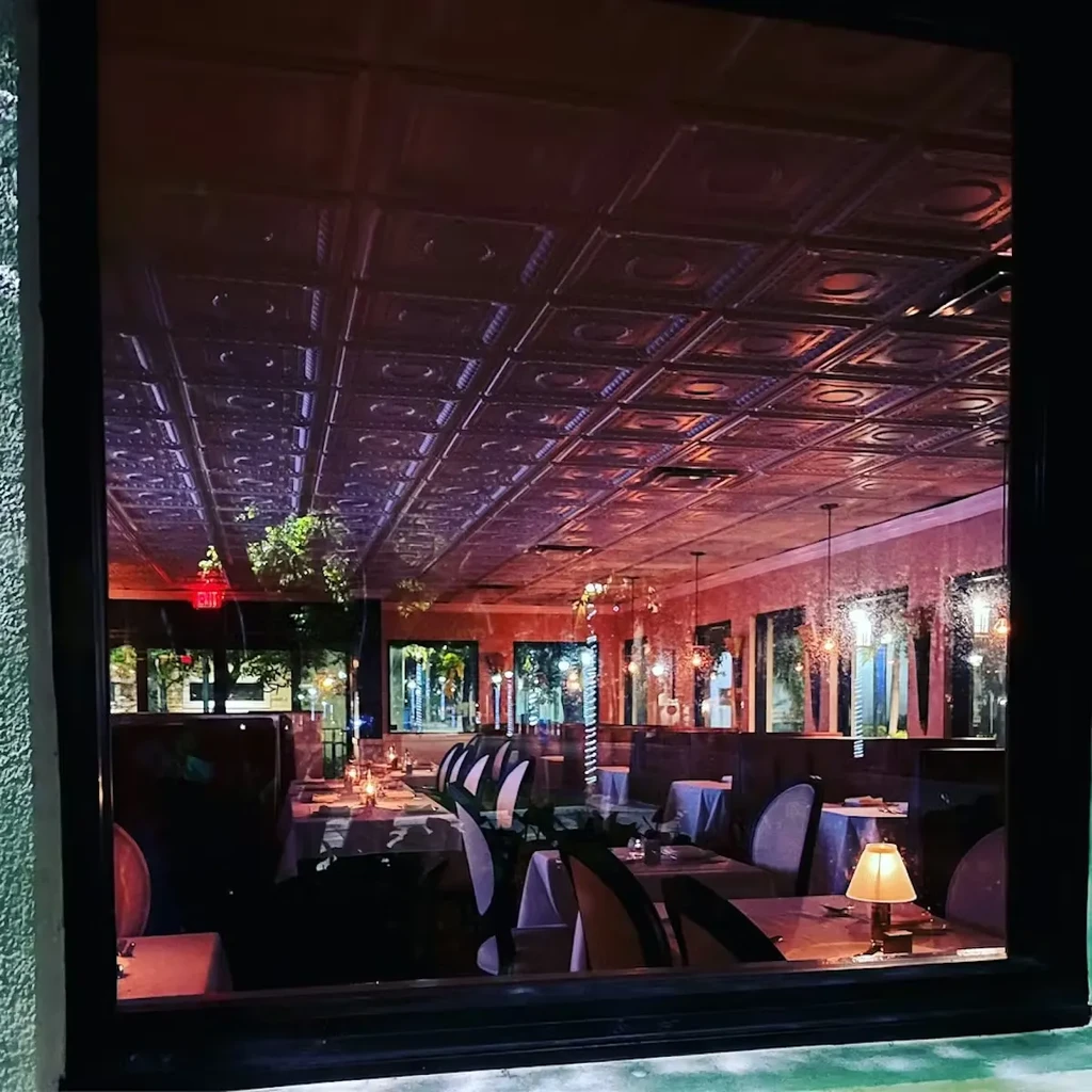 Warm, intimate restaurant interior with patterned ceiling and set tables.