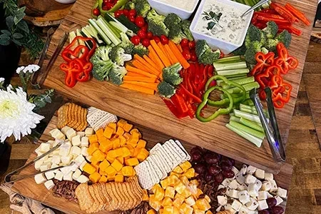 Rustic boards display colorful crudités, dips, cheese, and charcuterie.