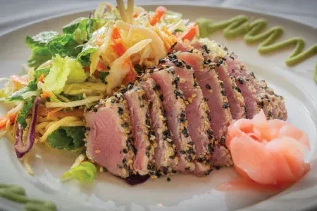High-angle view of plated sesame-crusted tuna, salad, pickled ginger, wasabi.