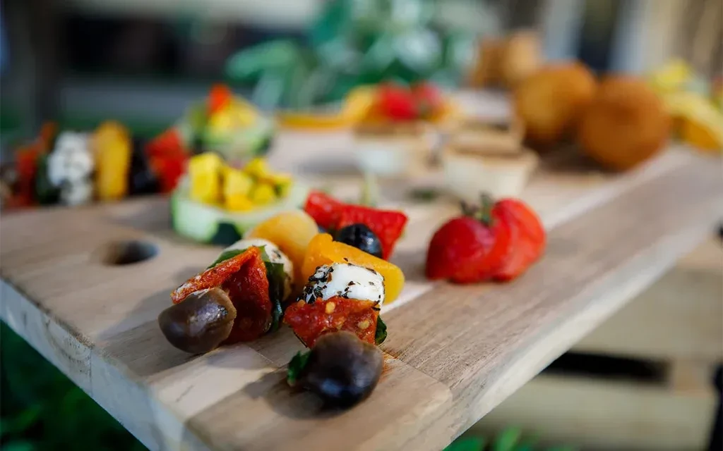 Assortment of colorful appetizers on a rustic wooden board outdoors.