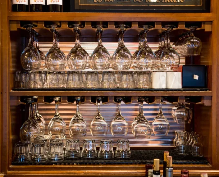 Clean wine glasses and tumblers neatly arranged on bar shelves.
