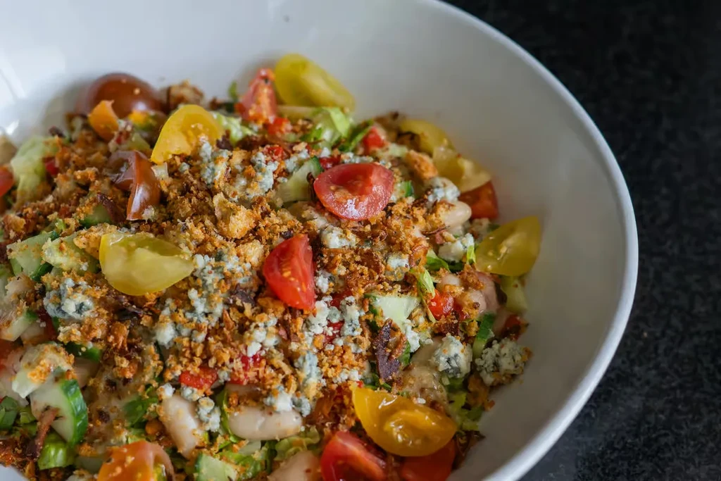 Close-up of salad with lettuce, tomatoes, blue cheese, beans, and crispy croutons.