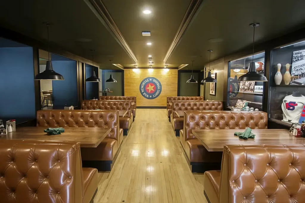 Empty dining area with tufted brown booths, memorabilia, and War Memorial emblem.