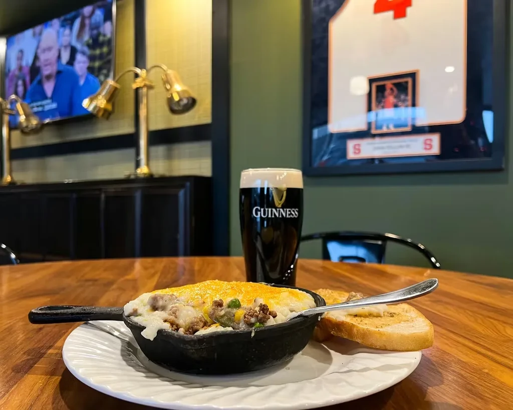 Skillet casserole, garlic bread, and Guinness on a pub table.