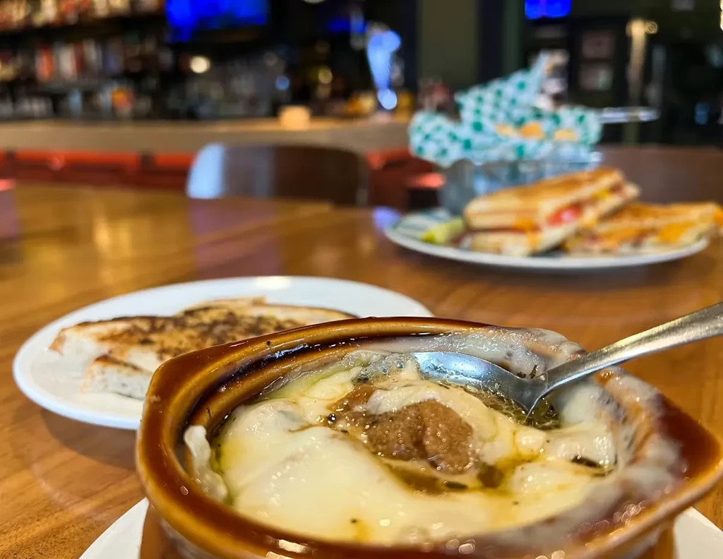 French onion soup with melted cheese, toasted bread, and a grilled sandwich.