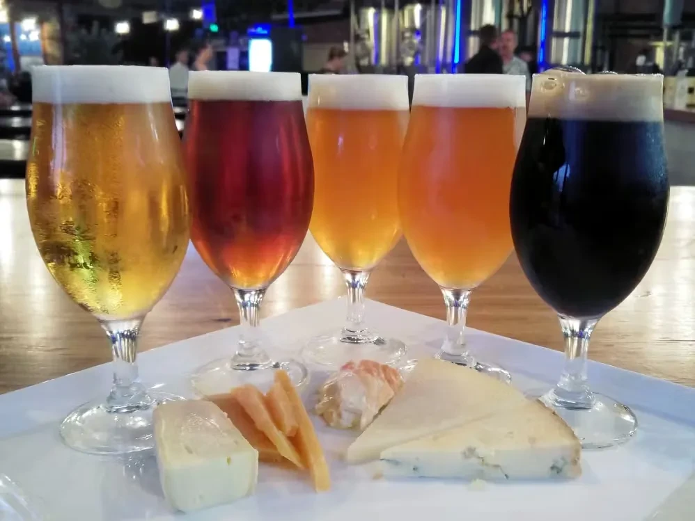 Close-up of a five-beer flight and cheese pairing on a tray.