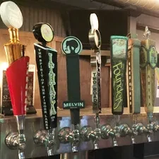 Close-up of seven distinct beer tap handles on a bar system.