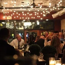 Evening restaurant interior: string lights, terracotta walls, blurred patrons.