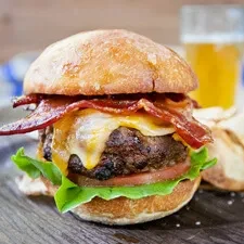 Gourmet cheeseburger with melted cheese, bacon, lettuce, and tomato.