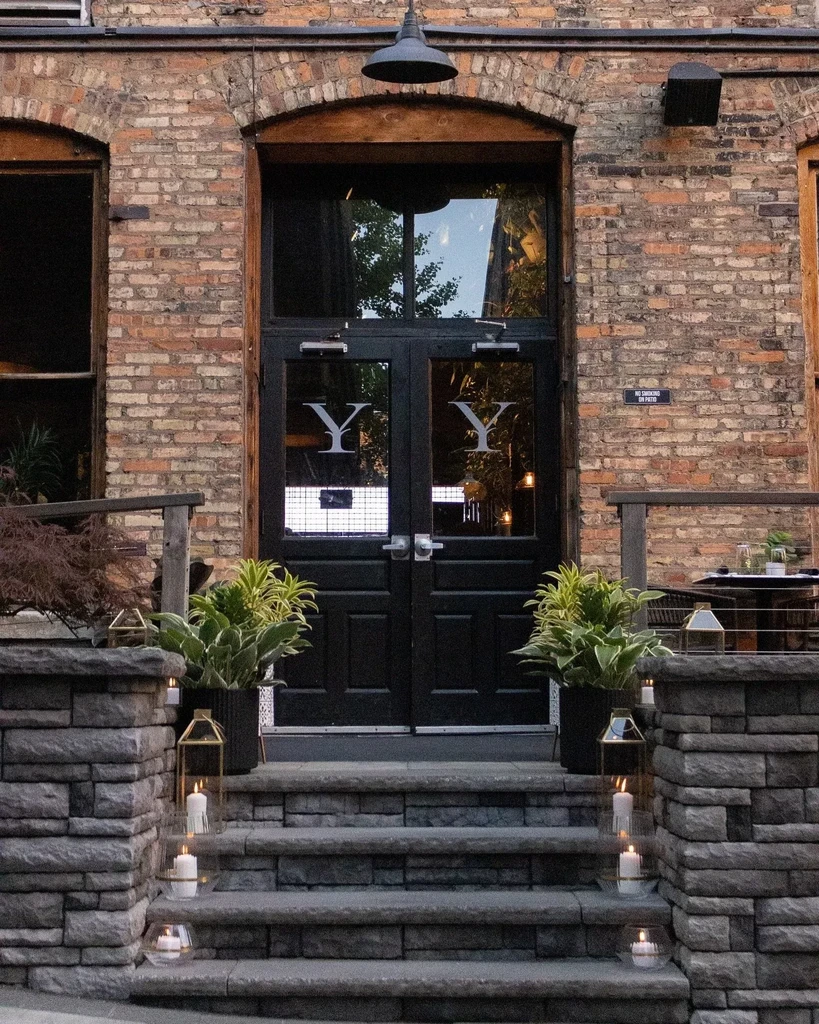Restaurant entrance with black 'YY' doors, stone steps, and glowing candles.