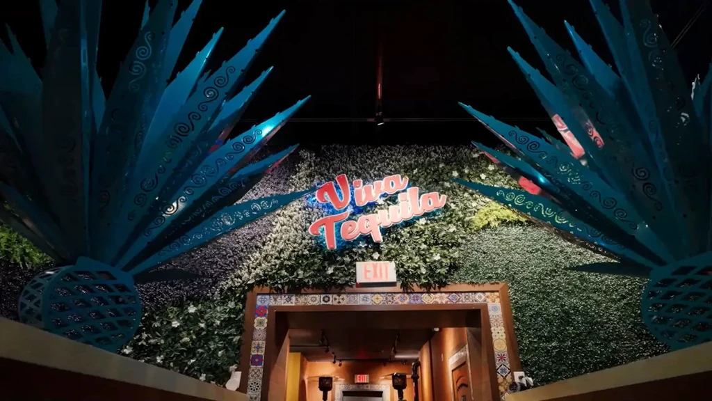 Restaurant entrance with "Viva Tequila" neon sign and teal agave sculptures.