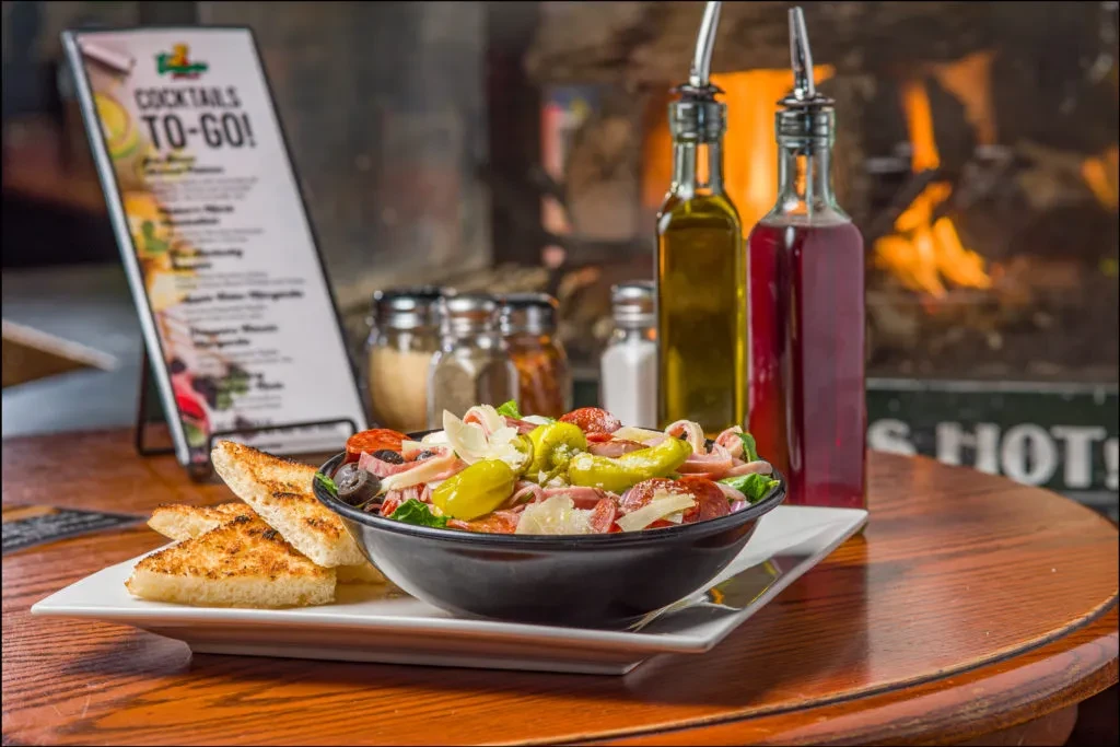 Salad with pepperoni, cheese, and bread in a restaurant.