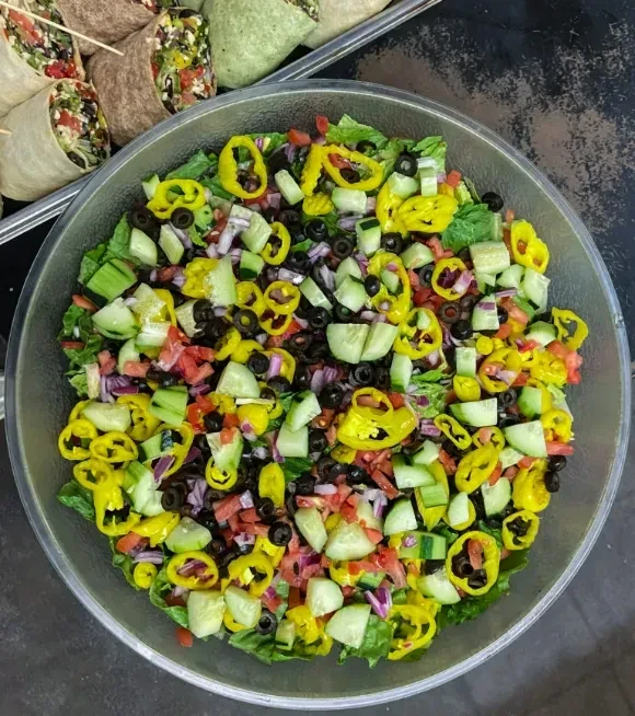 Overhead view of colorful salad with lettuce, tomatoes, onions; wraps.