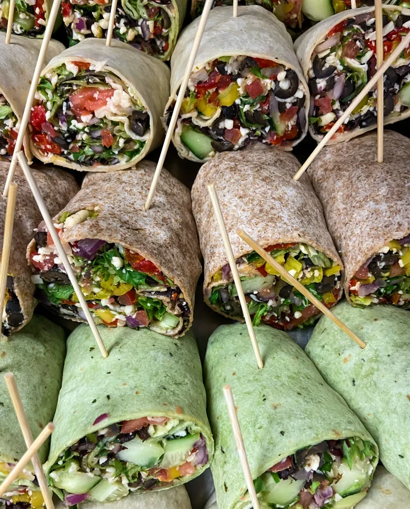 Assorted whole wheat and green wraps, cut to show colorful fillings.