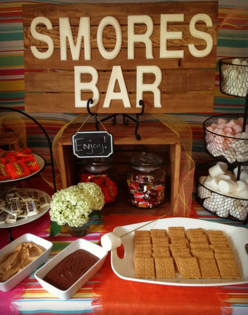 Rustic "SMORES BAR" setup with candies, marshmallows, graham crackers, and dips.