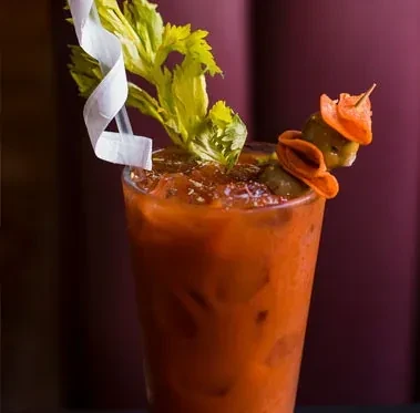 Elaborately garnished Bloody Mary with celery, pickled skewer, and straw.