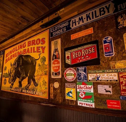 Rustic restaurant wall covered with vintage advertising signs and posters.