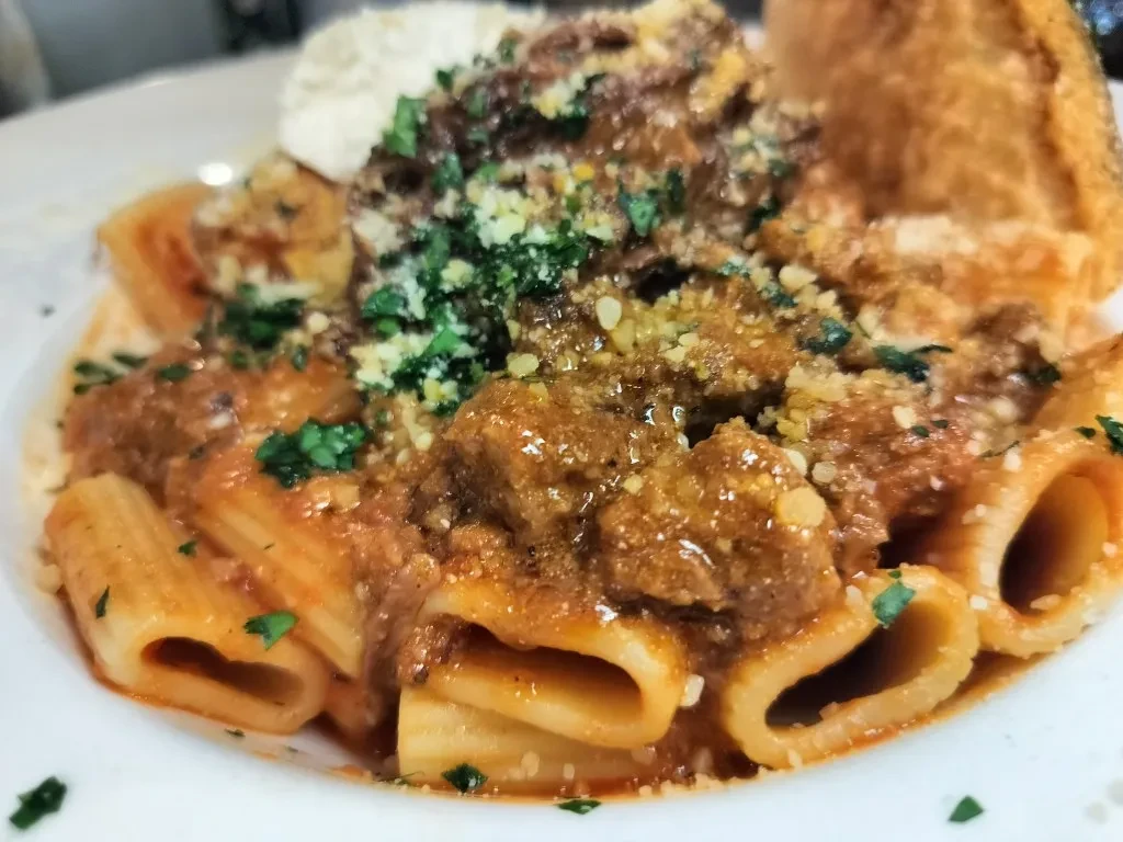 Tubular pasta with meat sauce, grated cheese, ricotta, and herbs.
