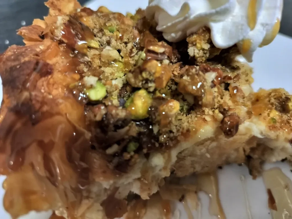 Flaky filo pastry with syrup, pistachios, other nuts, and whipped cream.