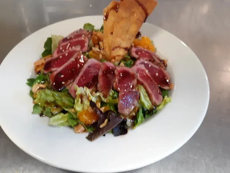 Seared tuna salad with greens, mandarin oranges, nuts, and a wonton.