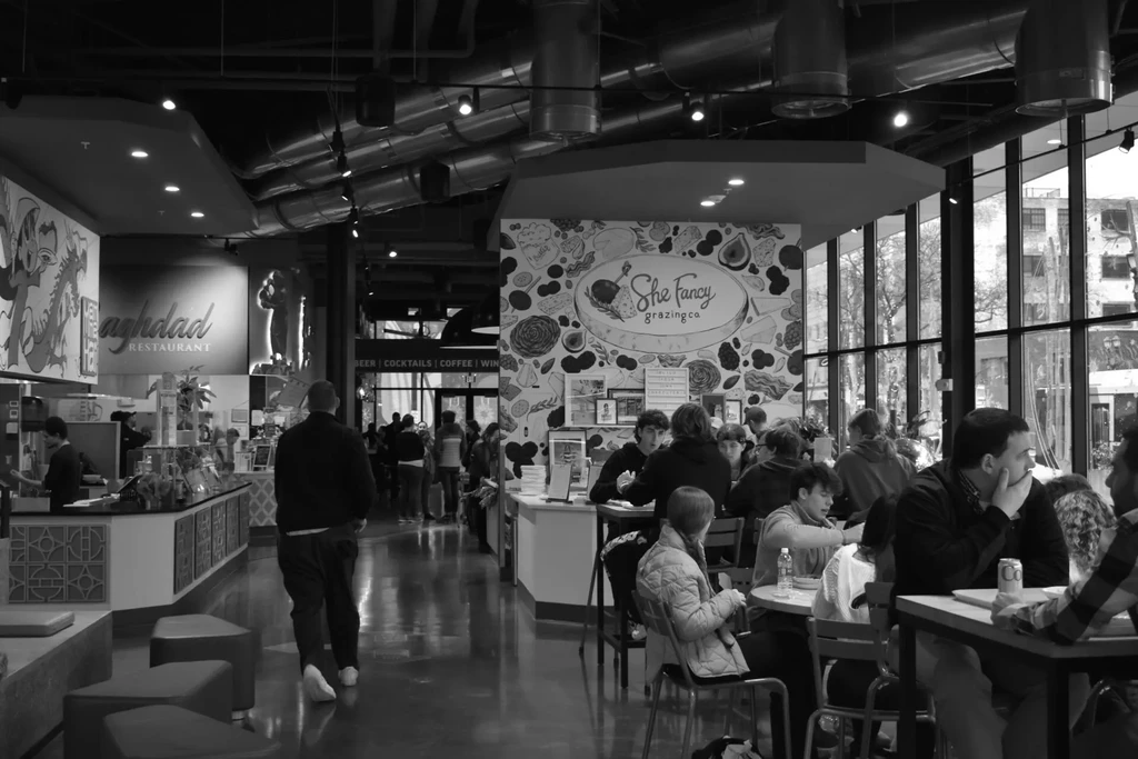 Large, industrial-chic food hall interior, bustling with people.