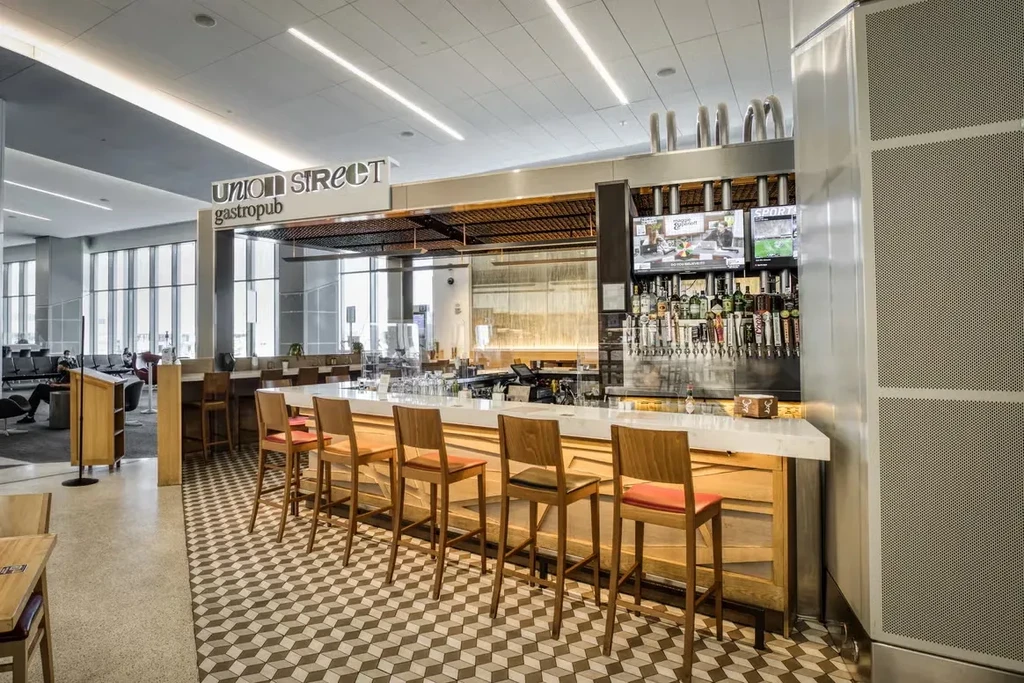 An empty gastropub with geometric floor tiles in an airport concourse.