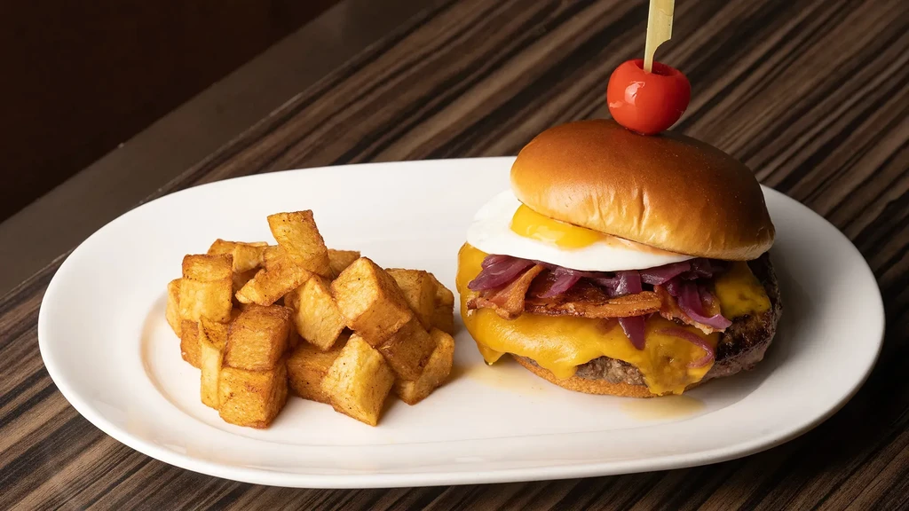 A white plate with a burger and a pile of fried potato cubes.