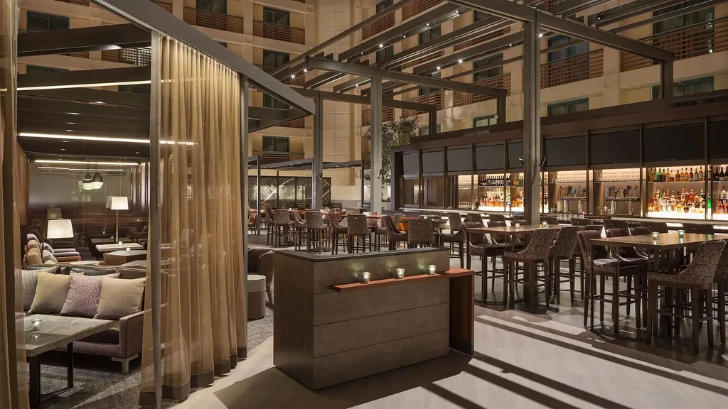 Modern hotel lounge and bar with high ceilings and various seating areas.