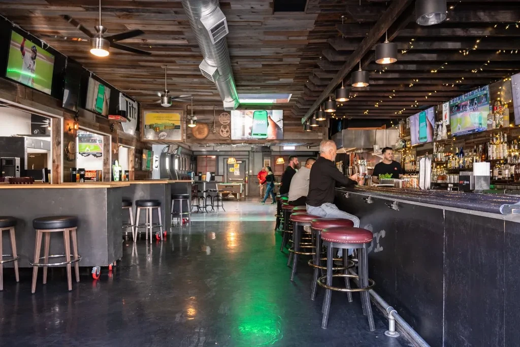 A lively bar with customers seated and a bartender working.