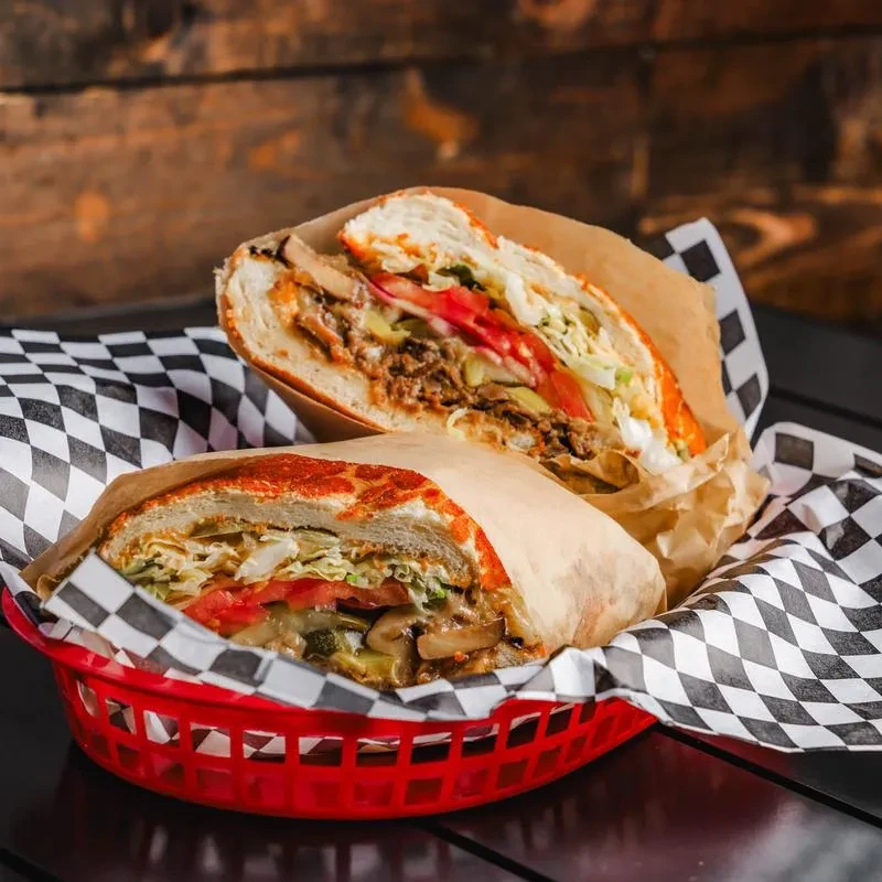 Two large sandwiches, cut in half, wrapped in paper.