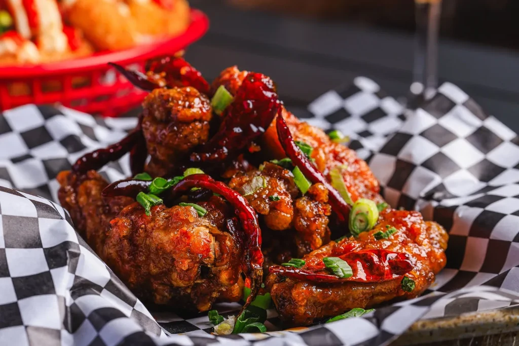 Spicy glazed chicken wings with dried red chili peppers and green onions.
