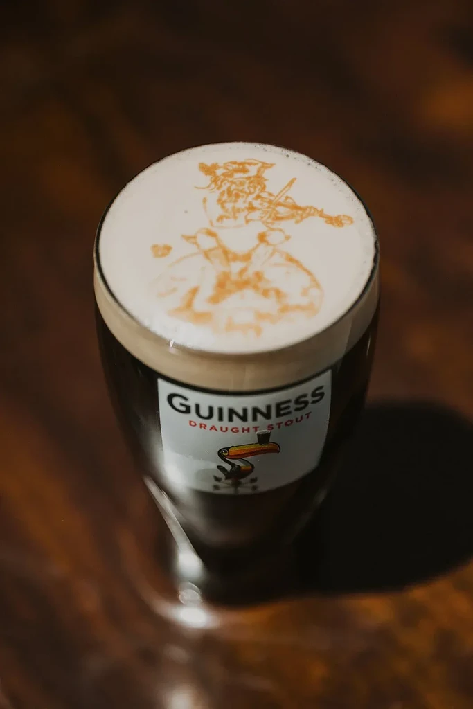 Guinness pint with a Toucan playing a violin in the foam.
