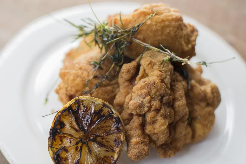 Fried chicken and a charred lemon slice on a white plate.