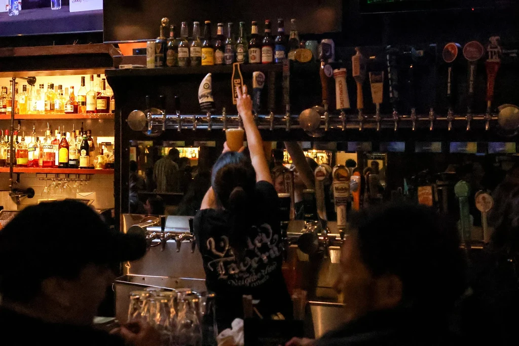 A bartender pouring a drink at a dimly lit bar.