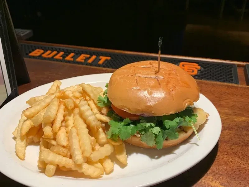 A plate with a burger and french fries on a bar top.