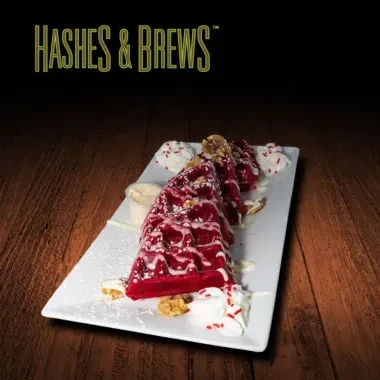 Four red velvet waffle triangles with cream, nuts, and sprinkles.