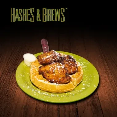 Chicken and waffles on a green plate under "HASHES & BREWS".