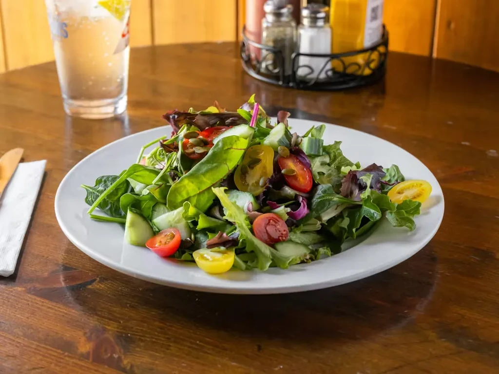 A fresh green salad with colorful tomatoes on a wooden table.