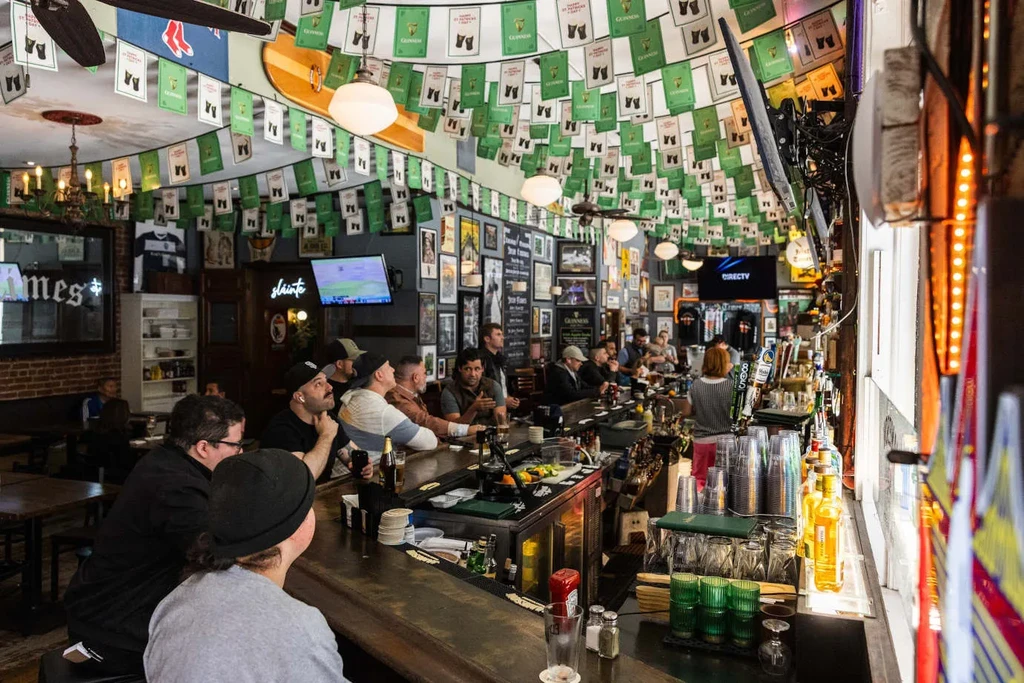 Patrons at a long wooden bar in a bustling Irish pub.