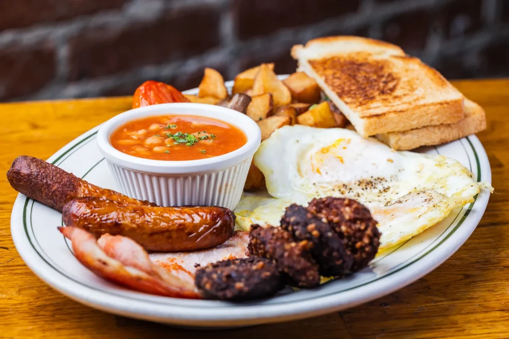 A full English breakfast with eggs, sausages, bacon, and beans.