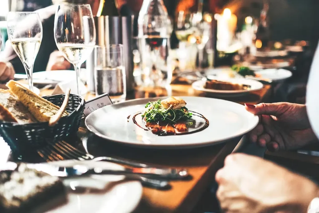 A person holds a plate with a meal in a restaurant setting.
