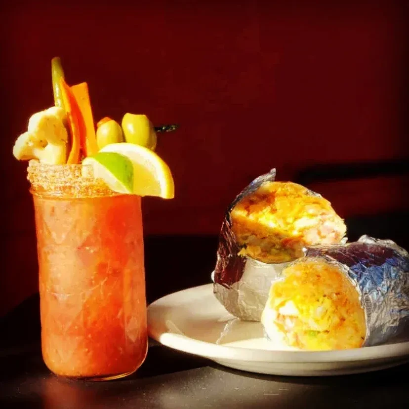 Spicy cocktail with garnished drink and two foil-wrapped sides.