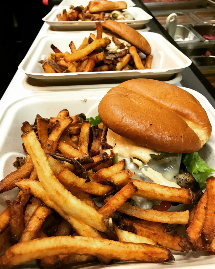 Take-out containers of fries and cheeseburgers on a counter.