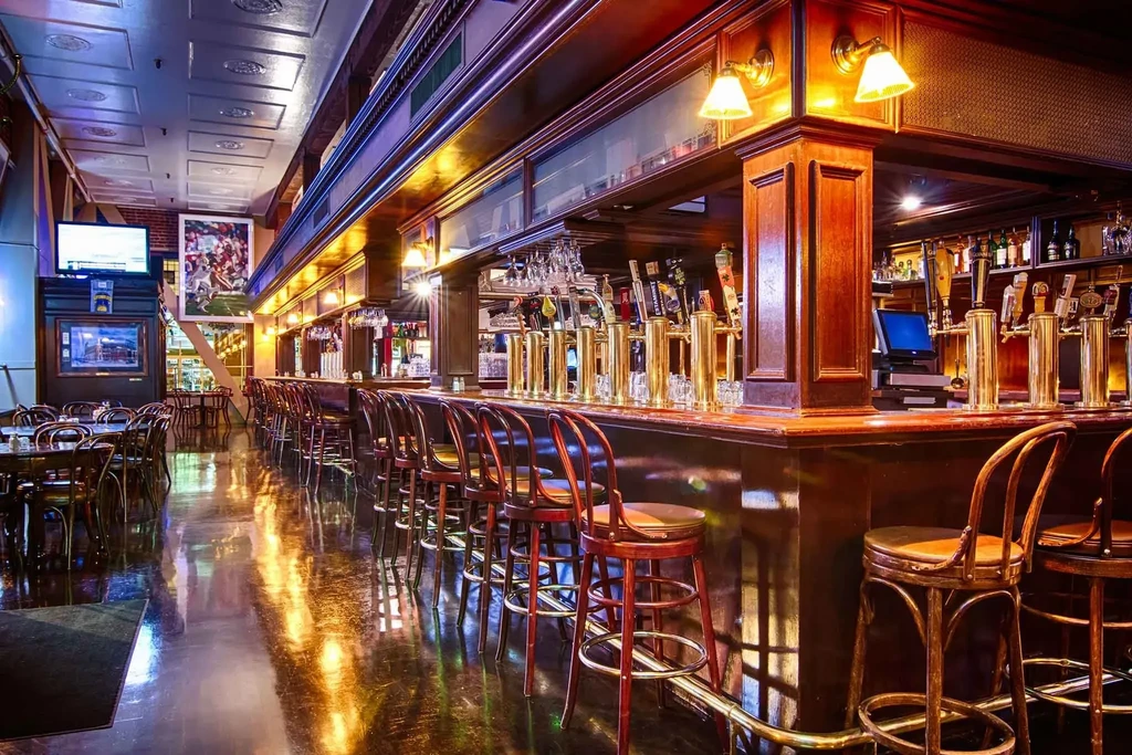 An empty bar with a long wooden counter and many taps.