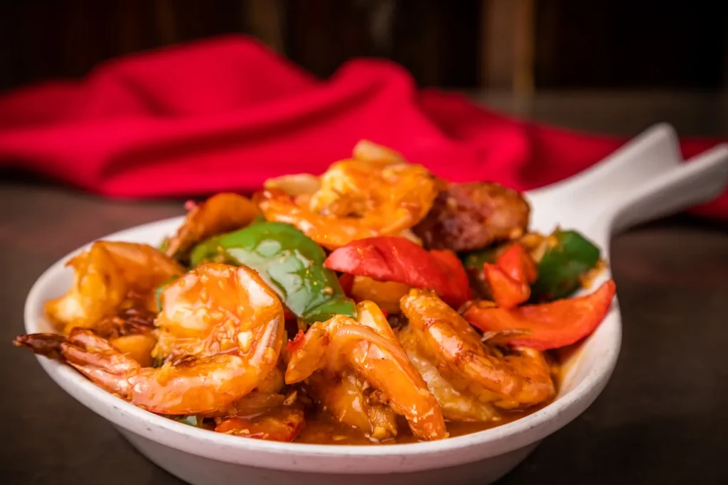 A dish of shrimp stir-fry with peppers in a white bowl.