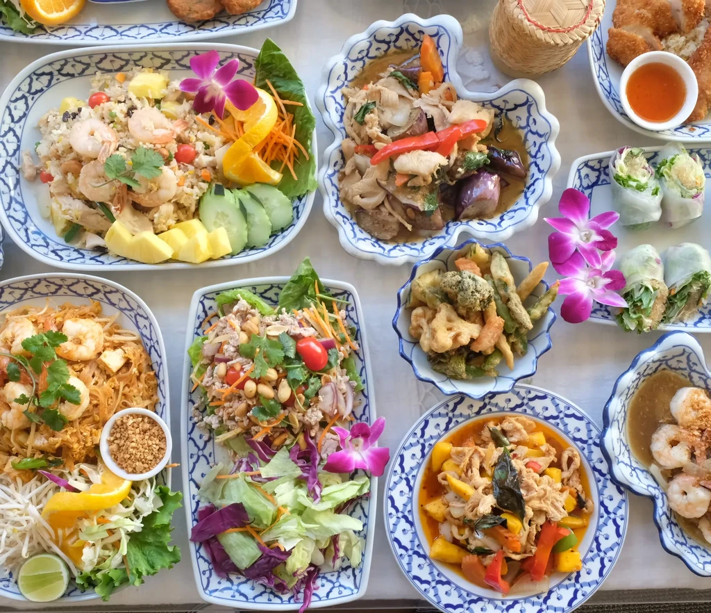 A table covered with various Thai dishes in decorative bowls and plates.