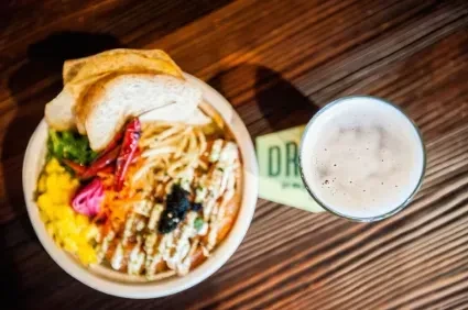 Overhead shot of a colorful poke bowl and a pint of beer.